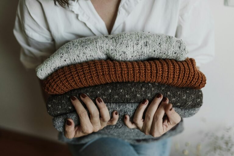 Woman holding organized stack of sweaters